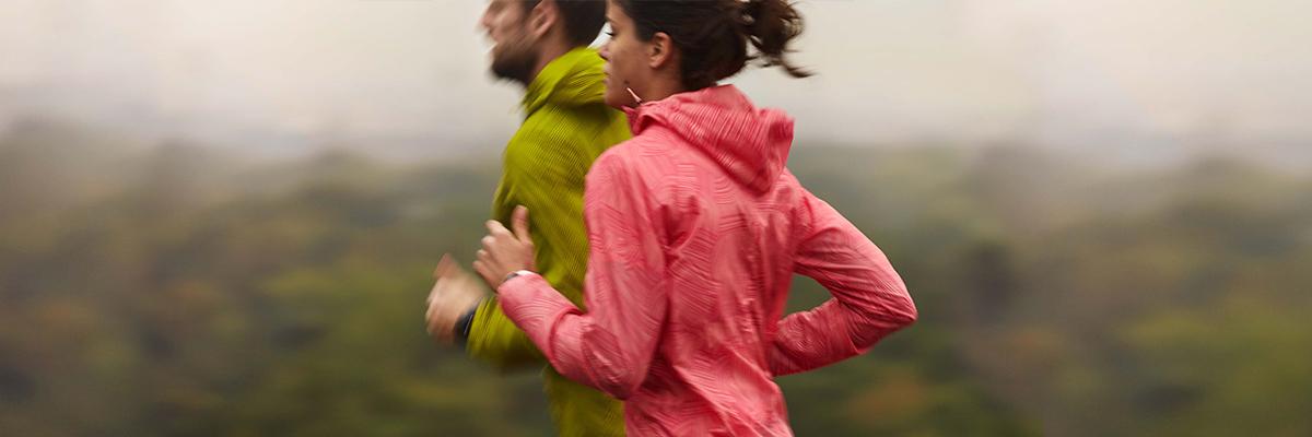 Eine Frau und ein Mann trainieren für einen 10 km Lauf bei regnerischem Wetter.