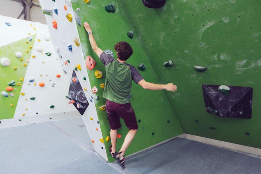 Ein Mann macht die "offene Tür" beim Bouldern in der Boulderhalle