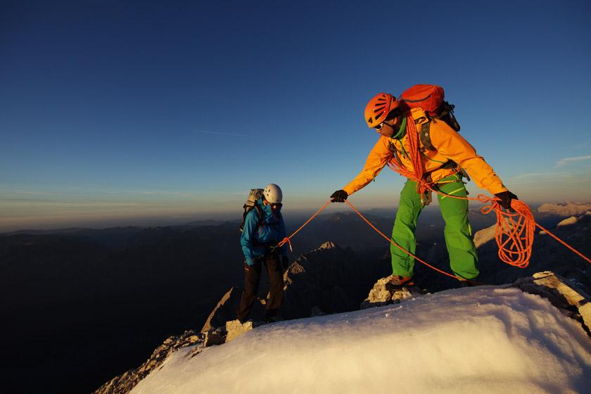 Zwei Kletterer klettern in einer bergigen Schneelandschaft bei Dämmerung