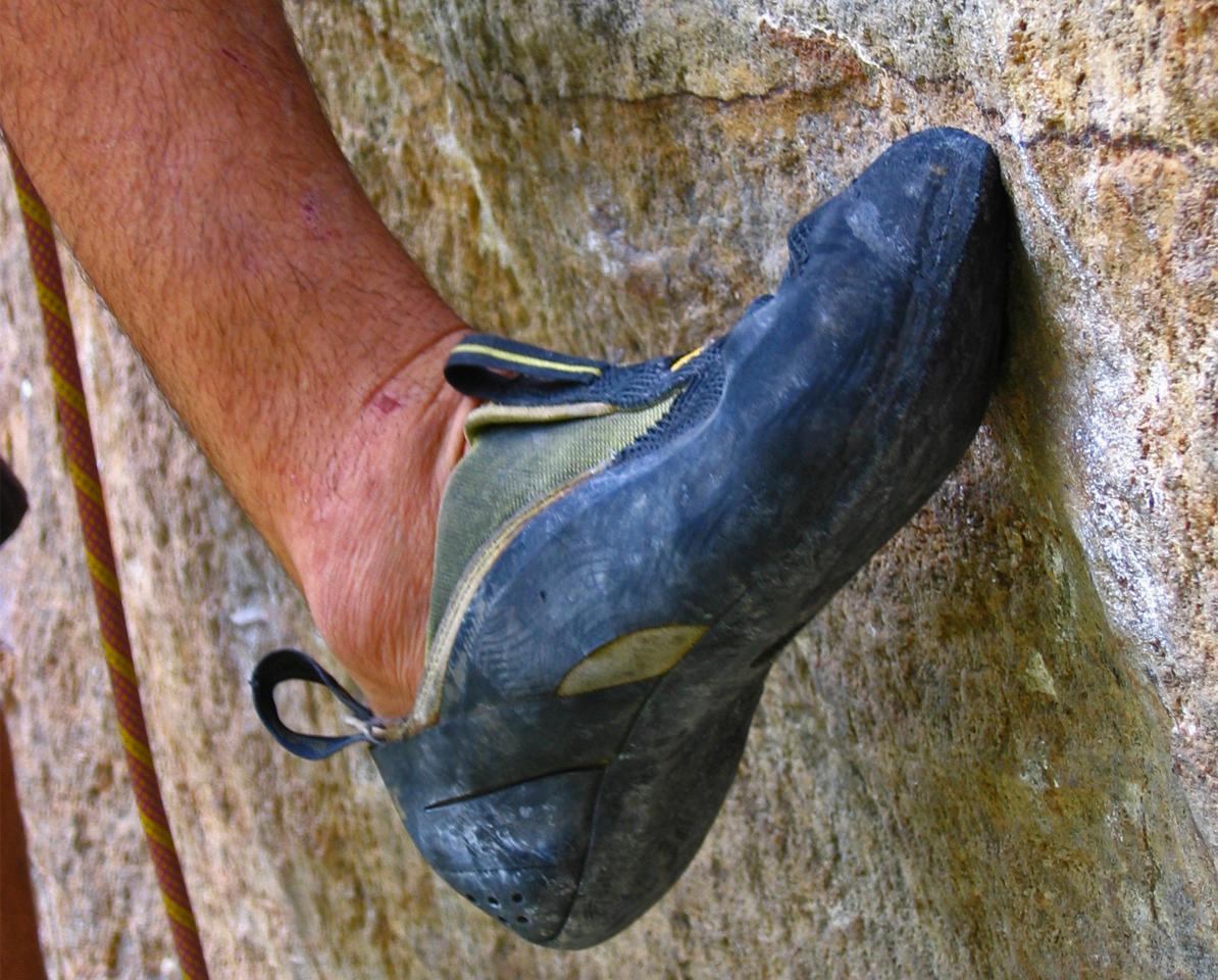 Nahaufnahme des Kletterschuhs einer kletternden Person am Fels