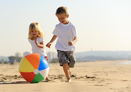 Zwei Kinder spielen mit einem Ball am Strand