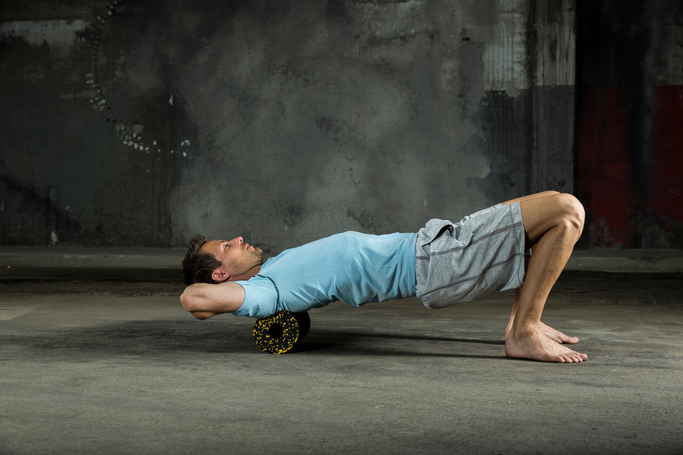 Ein Mann zeigt, wie man mit einer Blackroll Schulterverspannungen l&ouml;st.