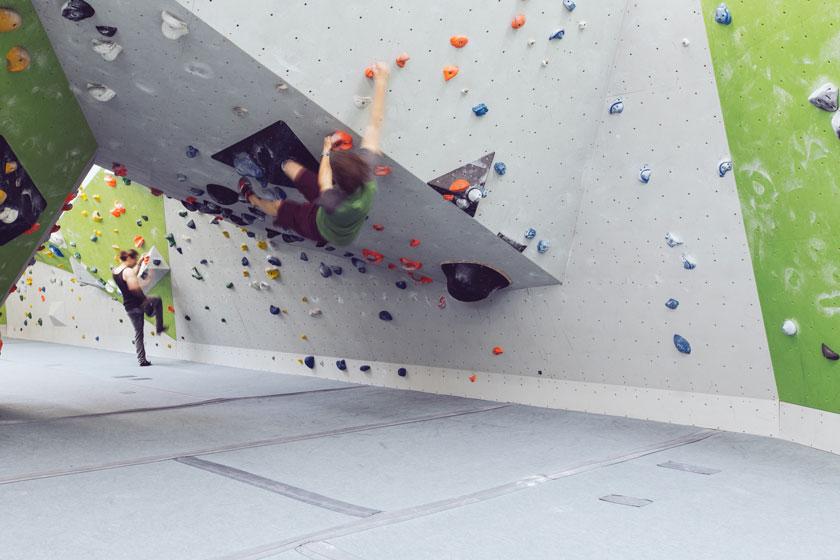 Ein Boulderer hängt kopfüber in einem Bouldertunnel.