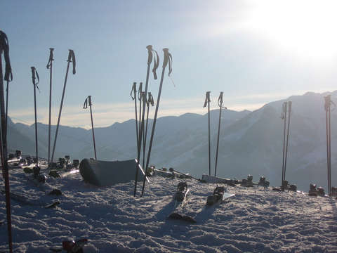 Viele verschiedene Skistöcke stehen vor einer Hütte in den Bergen