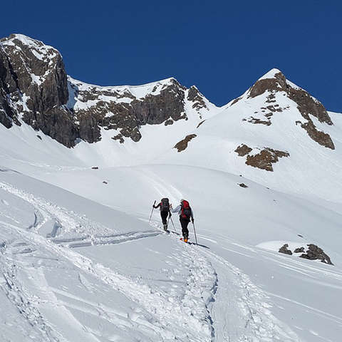 2 Skitourer in einer weiten Schneelandschaft unterwegs.