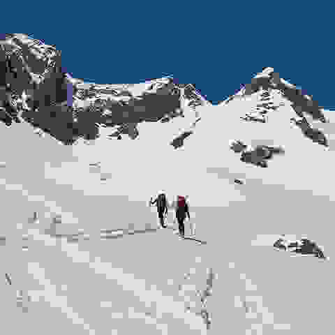 2 Skitourer in einer weiten Schneelandschaft unterwegs.