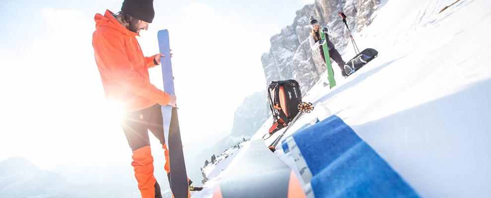 2 Menschen ziehen ihre Skifelle auf und ein Skifell liegt am Boden 