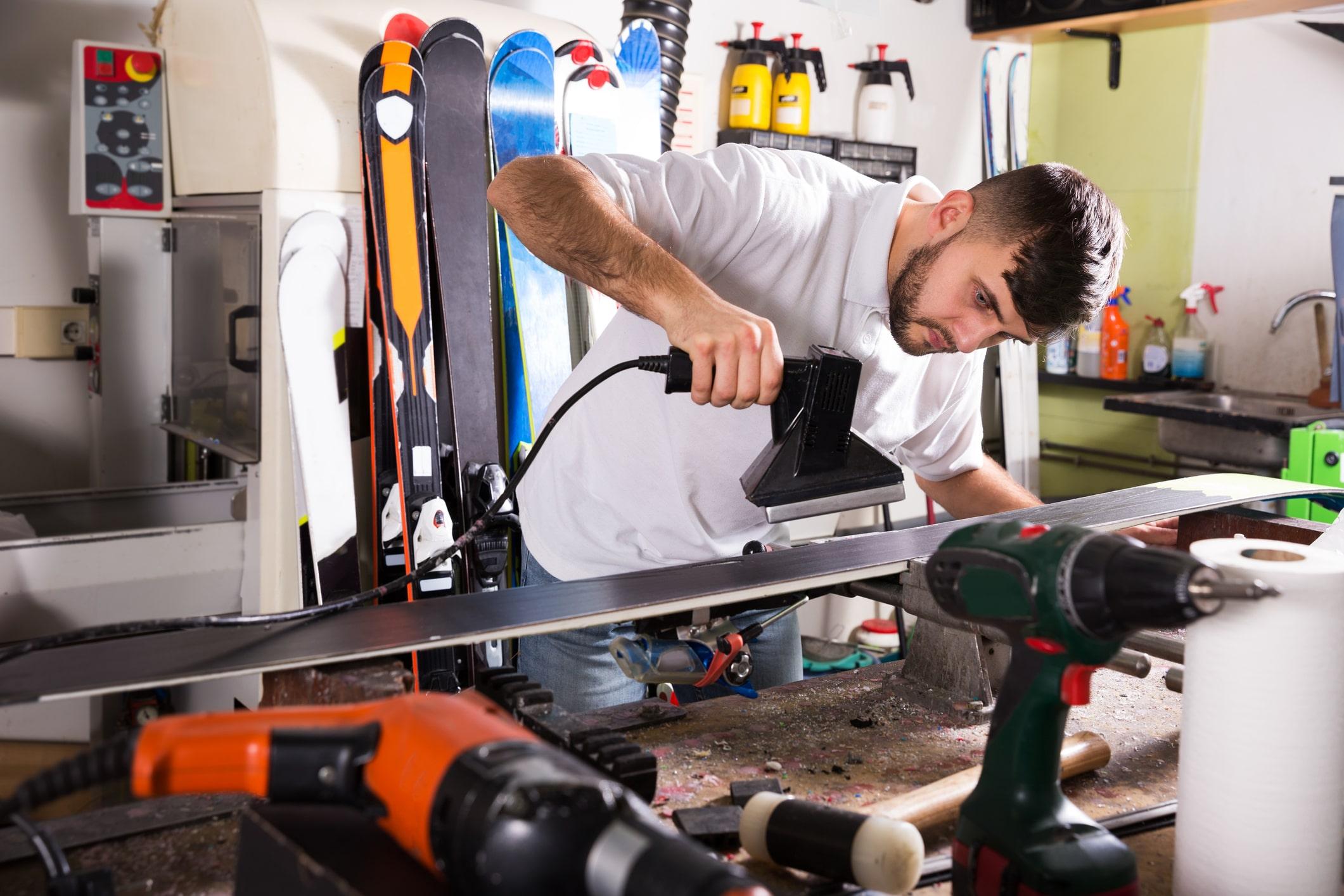 Ein Mann wachst einen SKi mit einem Heisswachsger&auml;t
