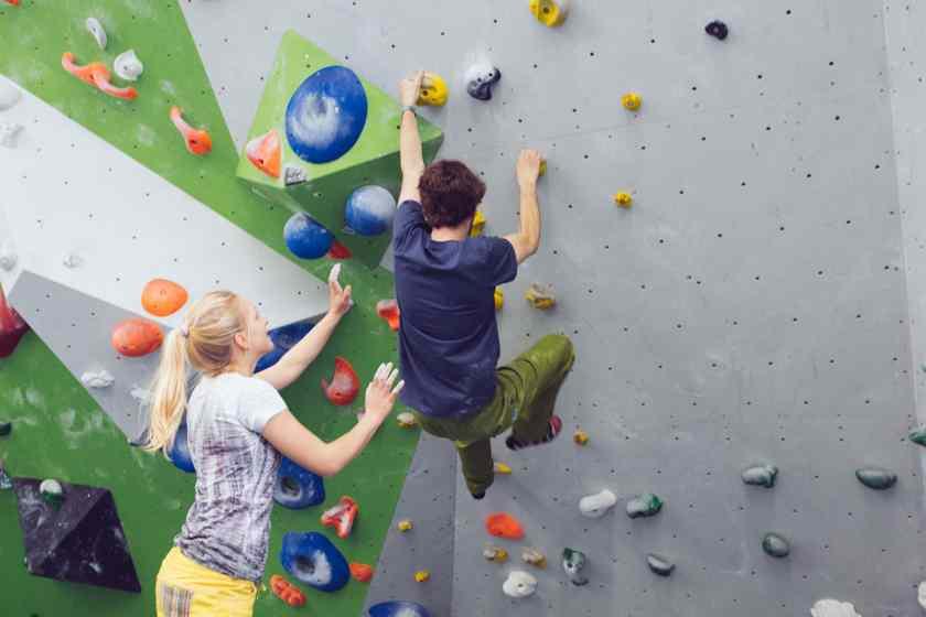 Eine Frau spottet einen Mann beim Bouldern