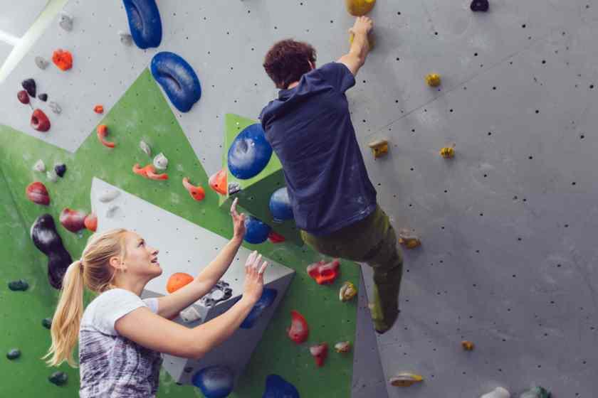 Eine Frau spottet einen Mann beim Bouldern