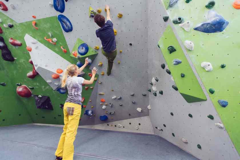 Eine Frau spottet einen Mann beim Bouldern