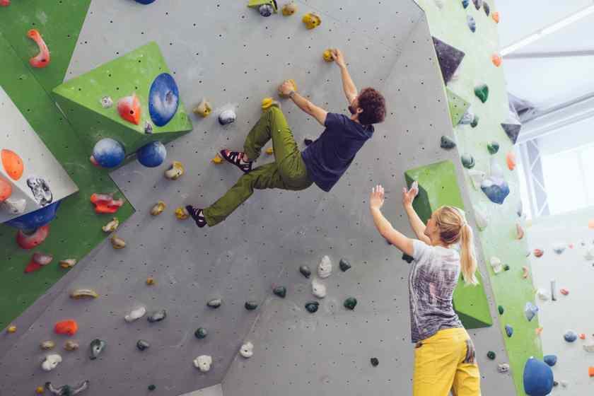 Eine Frau spottet einen Mann beim Bouldern