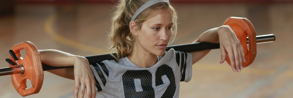 Eine Frau beim Training mit einer Langhantel im Nacken im Bereich der Superkompensation.