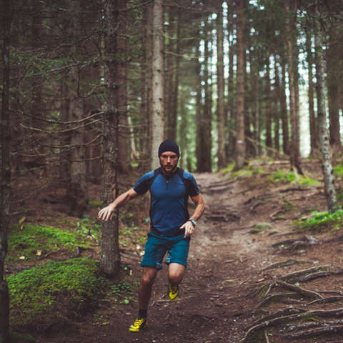 Ein Mann läuft im Wald bergab. 