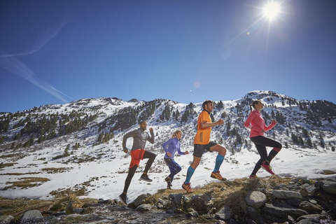 4 Trailrunning Läufer abgebildet vor einem Bergpanorama. 
