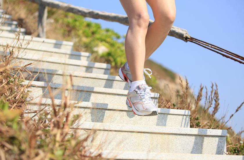 Die Beine einer Frau, die gerade in Laufschuhen eine Treppe hinab läuft.