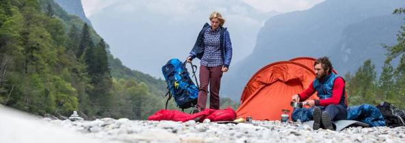 Ein Mann und eine Frau stellen ein wasserdichtes Zelt auf.