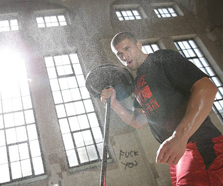 Ein Mann trainiert in einer Lagerhalle mit einer Langhantel.